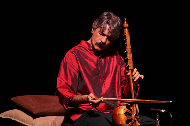 Kayhan Kalhor wearing a red silk shirt while playing a kamancheh