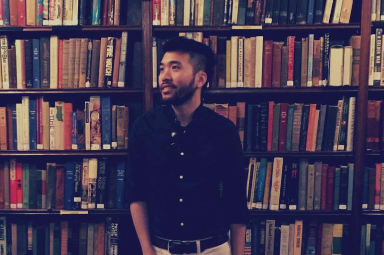 Baldwin Giang standing in front of a bookshelf