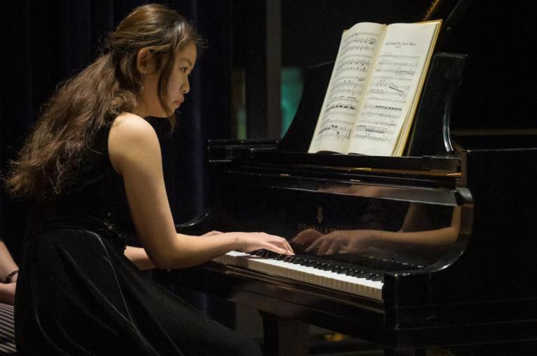 A woman sitting at the piano with music on the stand