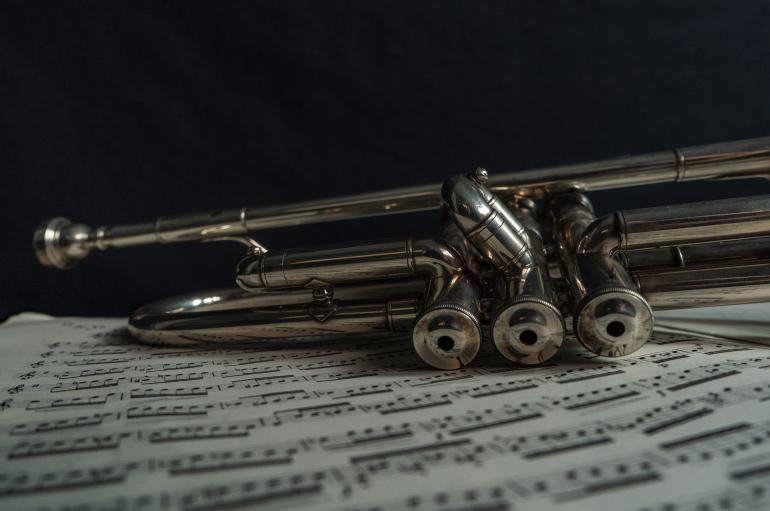 Close up of a trumpet resting on top of sheet music