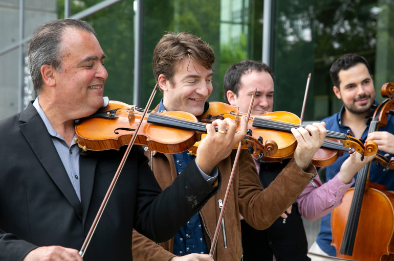 A group of four men play string instruments.