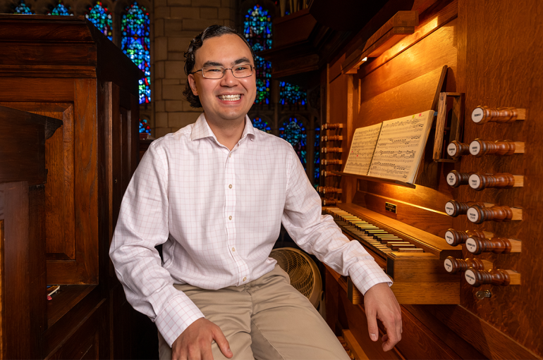 Jacob Reed smiles, sitting next to the Reneker Organ keyboard. Photo by Jason Smith