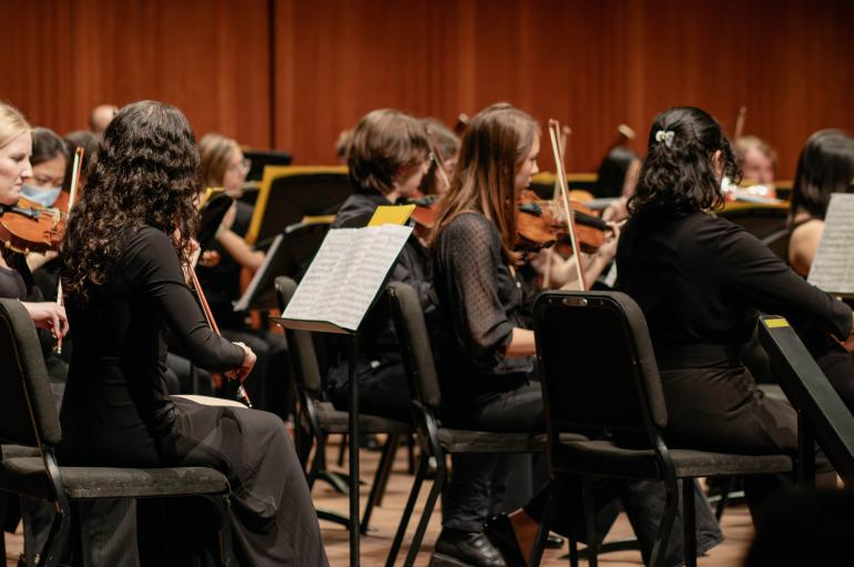 Violinists wearing all black perform on stage