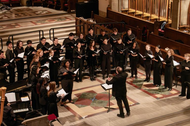 A choir wearing all black sings in a chapel