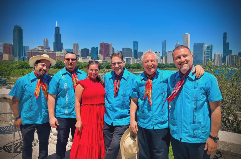 Sonés de México Ensemble - 6 musicians wearing red and blue clothing posed in front of the Chicago skyline
