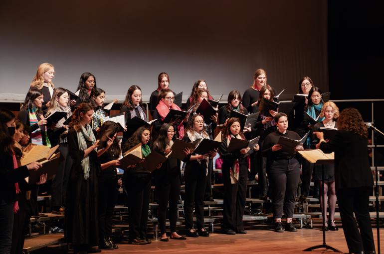 A choir in all black performs on a stage