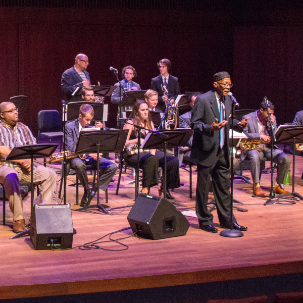 Mwata Bowden on stage addressing the audience in front of the jazz x-tet