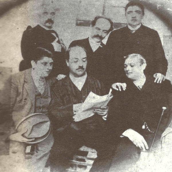 Archive photo showing a group of Italian men sitting around a newspaper in the late 1800s. Alessandro Moreschi is on the bottom left, and Giovanni Cesari is on the bottom right.