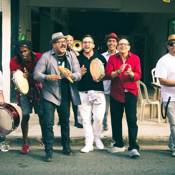 Plena Libre playing drums and horns, singing, and dancing