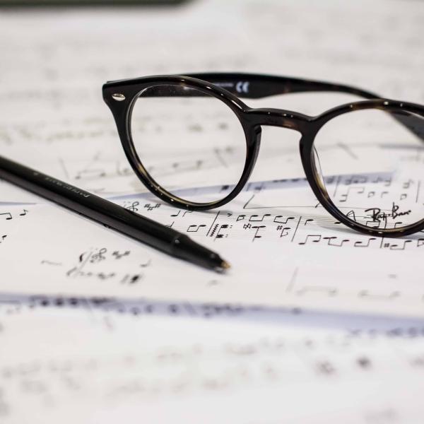 a pair of glasses and a pen resting on a musical score